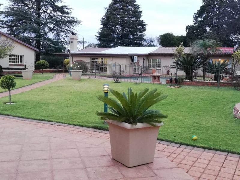 Spacious rear garden featuring a paved patio area, well-maintained lawn, and a swimming pool, providing an ideal setting for outdoor relaxation and entertainment.