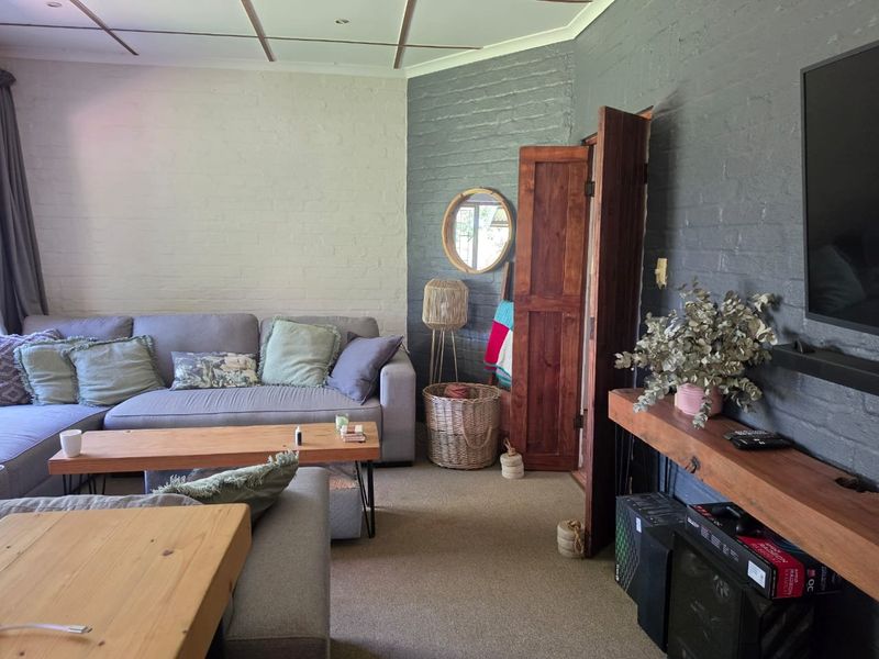 A cozy living room featuring painted exposed brick walls, recessed ceiling lighting, and a warm timber door, creating a comfortable and inviting atmosphere.
