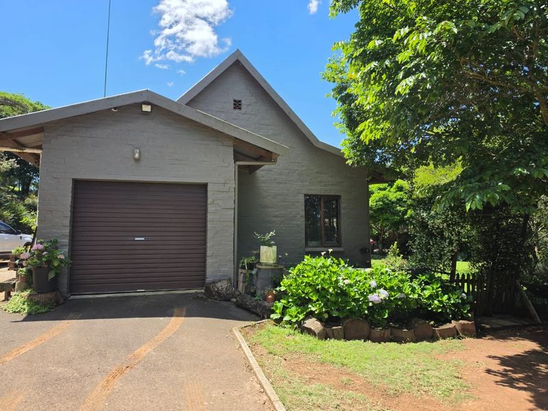 Front exterior view of the property featuring a single garage, asphalt driveway, and established garden landscaping.