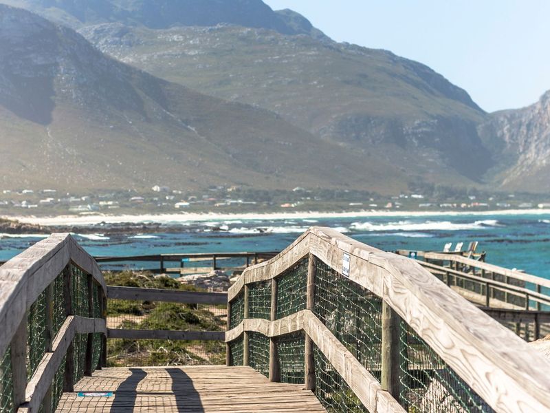 Scenic view of the coastline and mountains from a wooden boardwalk path.