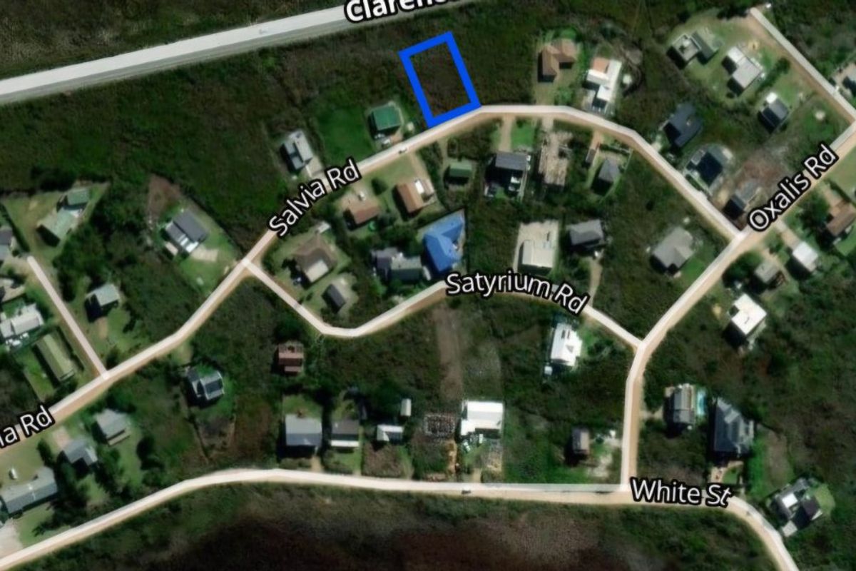 Aerial view of a vacant residential land plot highlighted in blue, situated within a developed coastal neighborhood.