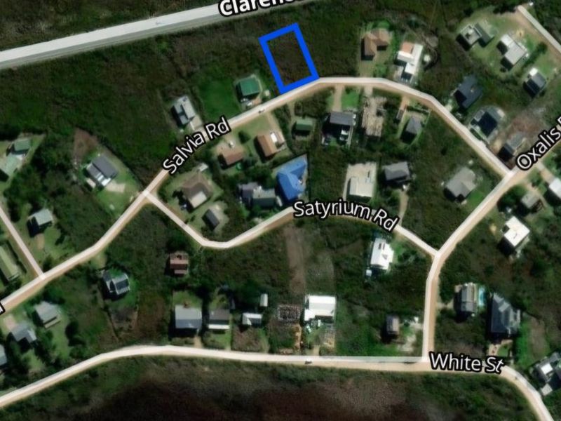 Aerial view of a vacant residential land plot highlighted in blue, situated within a developed coastal neighborhood.