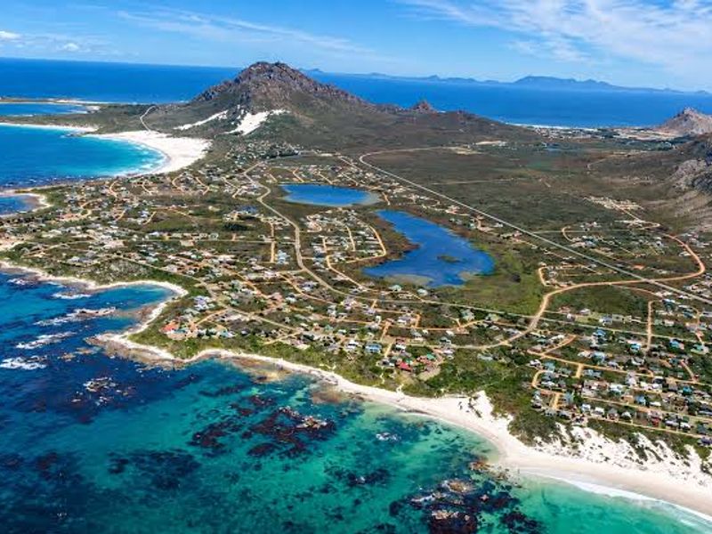 An expansive aerial view of a coastal residential area featuring natural lagoons, sandy beaches, and mountain vistas.