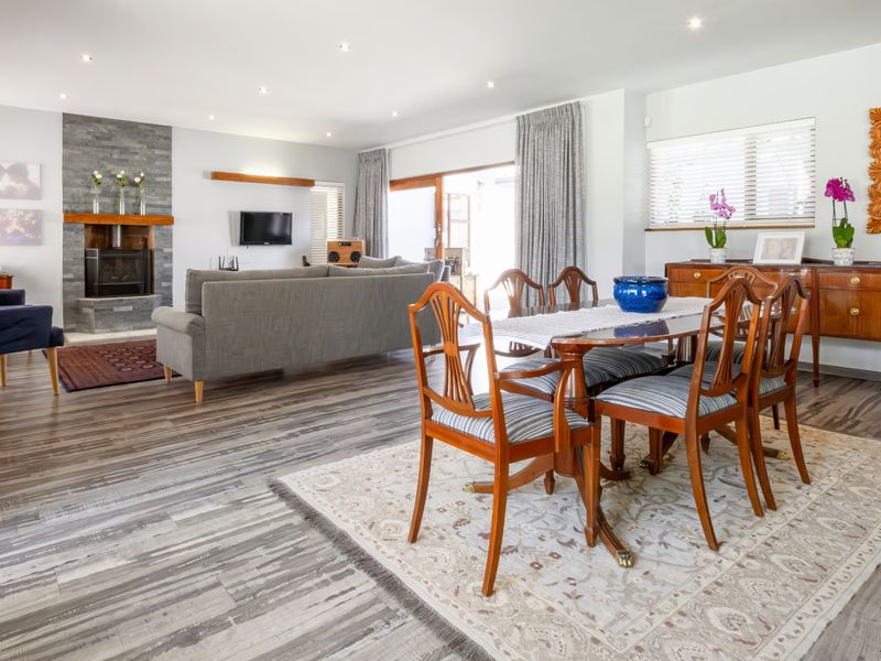 Spacious open-plan living and dining area featuring modern laminate flooring, a stone-clad fireplace, and large sliding doors providing natural light.