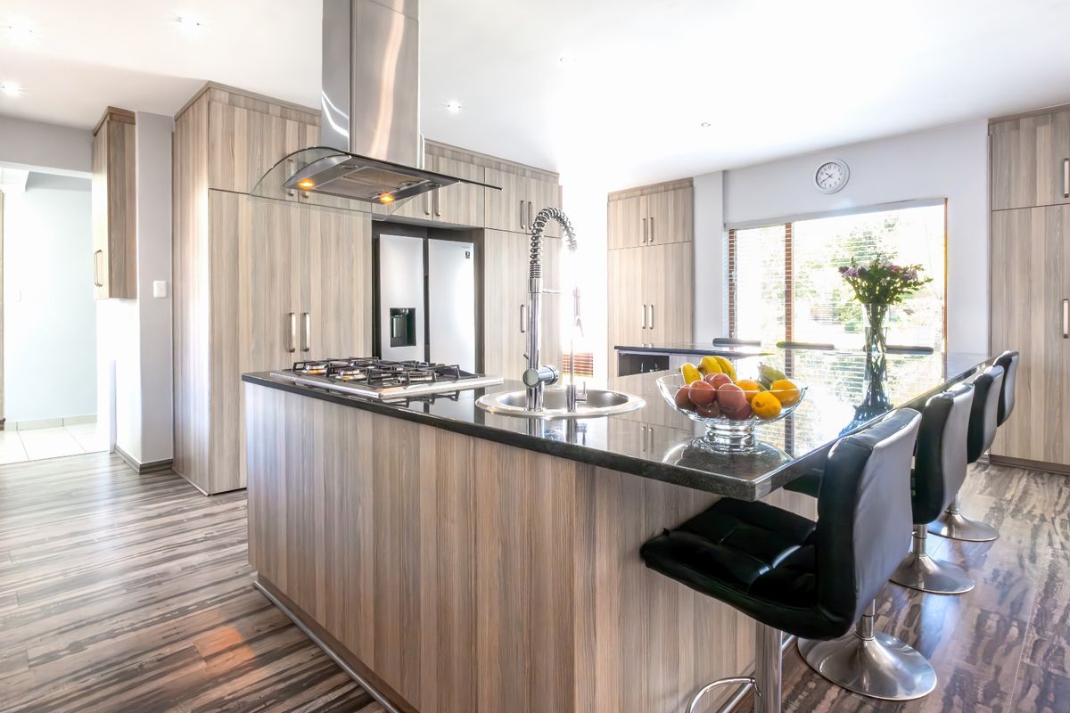 Modern kitchen featuring a large island with a gas hob, granite countertops, integrated cabinetry, and a sleek gooseneck faucet.