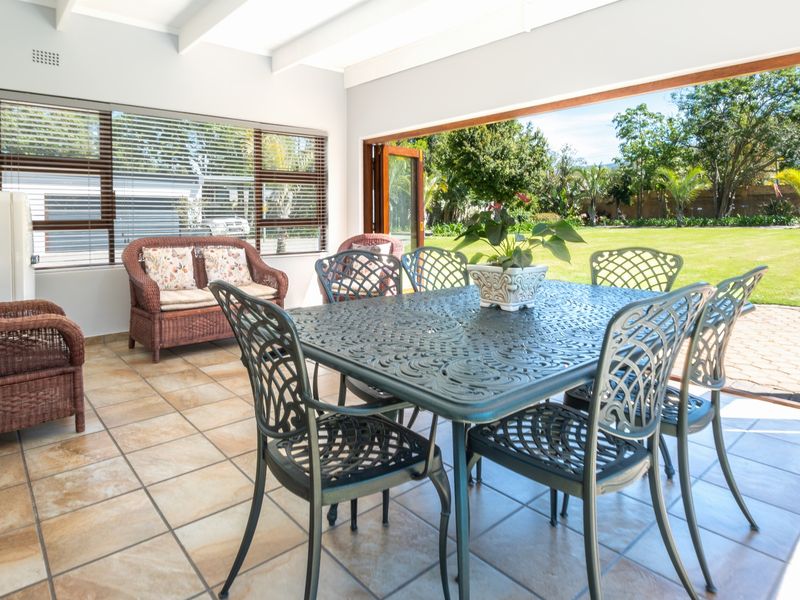 Spacious covered patio featuring tiled flooring, exposed beam ceiling, and large bi-fold doors opening directly onto the garden.