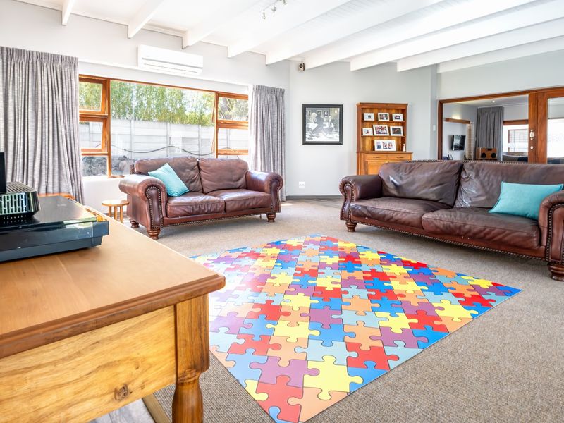 Spacious living room featuring exposed beam ceilings, large windows for natural light, and a wall-mounted air conditioning unit.