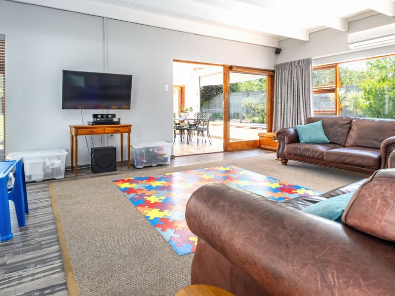 Spacious living room featuring exposed beam ceilings, split-system air conditioning, and large sliding glass doors providing seamless access to the outdoor patio area.