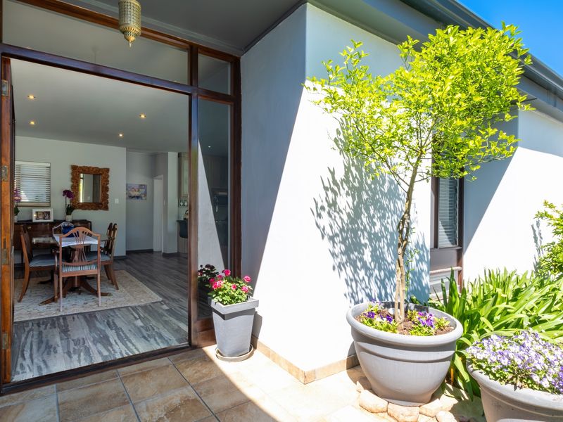 A well-maintained covered patio area featuring tiled flooring and large glass sliding doors that provide seamless access to the interior dining space.