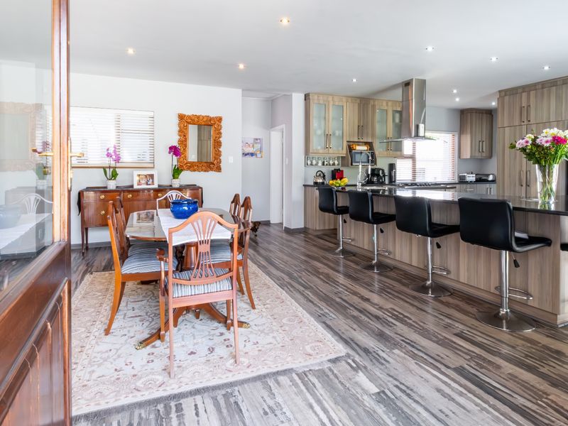 Spacious open-plan living and dining area featuring a modern kitchen with a large island, contemporary cabinetry, and durable laminate flooring throughout.
