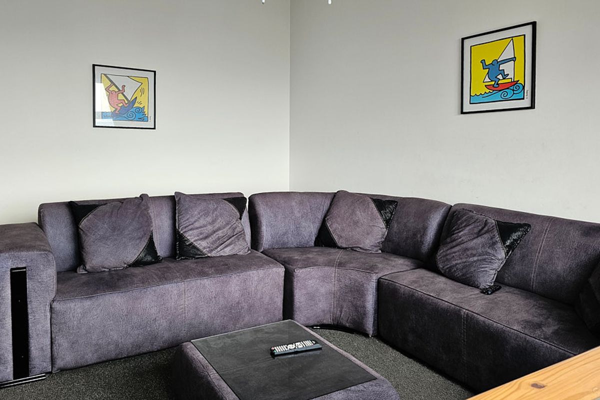 A comfortable living room area featuring neutral wall finishes and carpeted flooring, providing a functional space for relaxation.