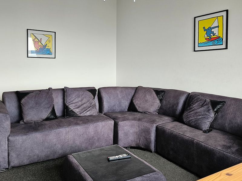 A comfortable living room area featuring neutral wall finishes and carpeted flooring, providing a functional space for relaxation.