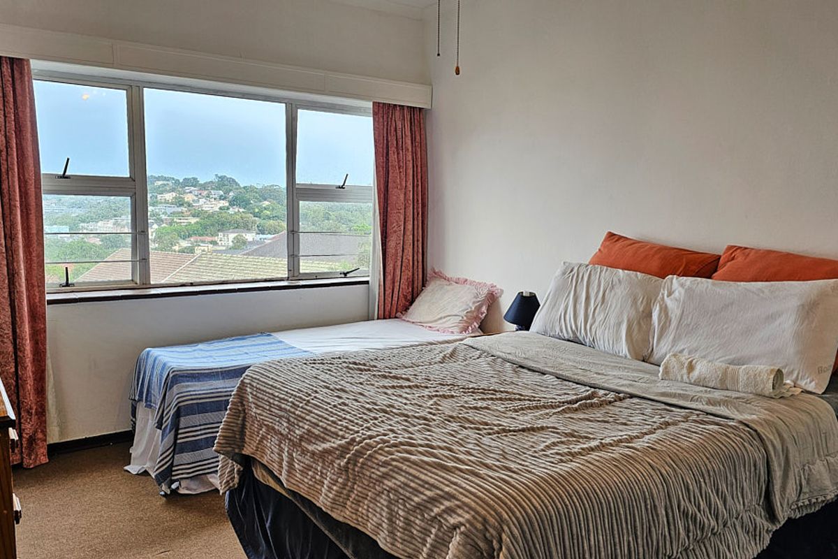 A bedroom featuring a large window with scenic views, carpeted flooring, and neutral wall finishes.