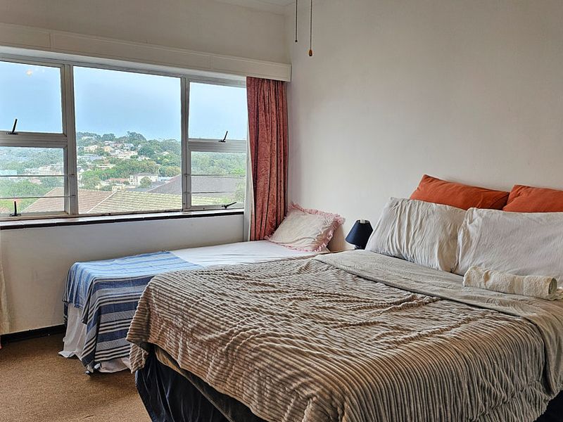 A bedroom featuring a large window with scenic views, carpeted flooring, and neutral wall finishes.