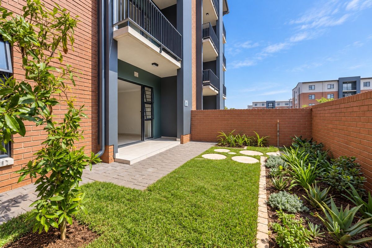 A well-maintained ground floor unit featuring a private paved patio, landscaped garden, and brick boundary wall, providing a pleasant outdoor living space.