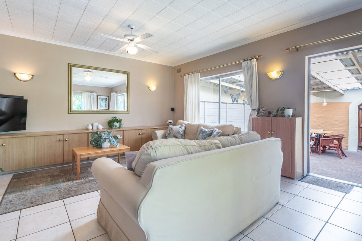Spacious living room featuring built-in cabinetry, tiled flooring, and a ceiling fan, with direct access to an outdoor patio area.