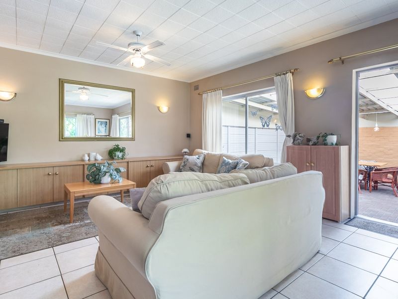 Spacious living room featuring built-in cabinetry, tiled flooring, and a ceiling fan, with direct access to an outdoor patio area.