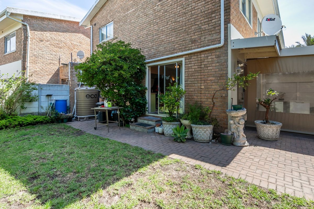 Rear exterior view of the apartment featuring a brick facade, paved patio area, sliding door access, and a water tank installation.