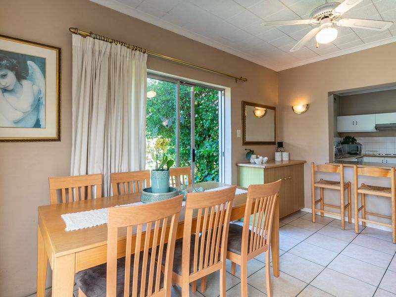 Open-plan dining and kitchen area featuring tiled flooring, a ceiling fan, and direct access to the garden through a sliding glass door.
