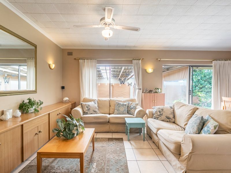 Spacious open-plan living and dining area featuring tiled floors, built-in cabinetry, ceiling fan, and sliding glass doors providing access to the outdoor space.