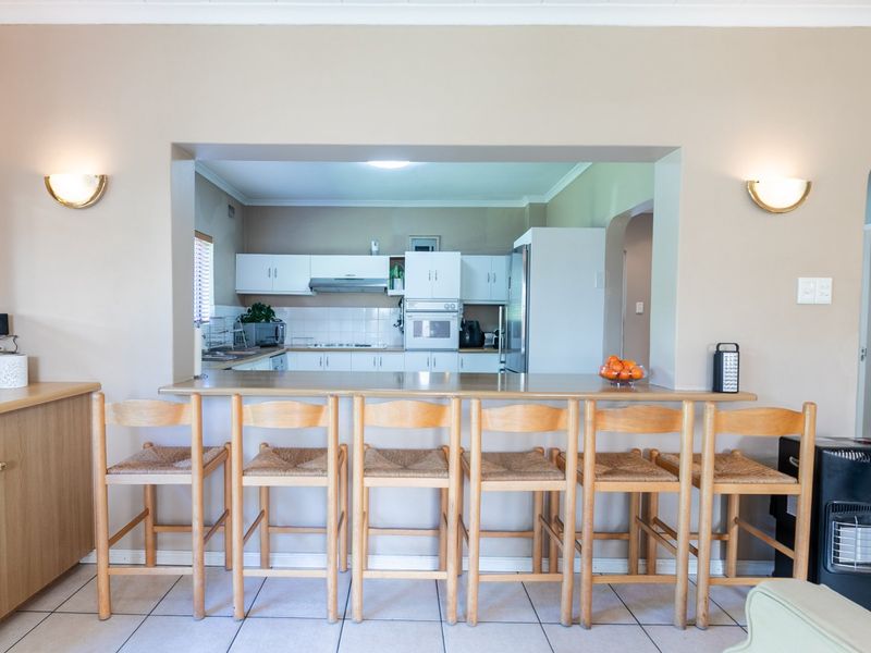 Open plan kitchen and living area featuring a breakfast bar, built-in cabinetry, and tiled flooring, creating a functional and connected living space.