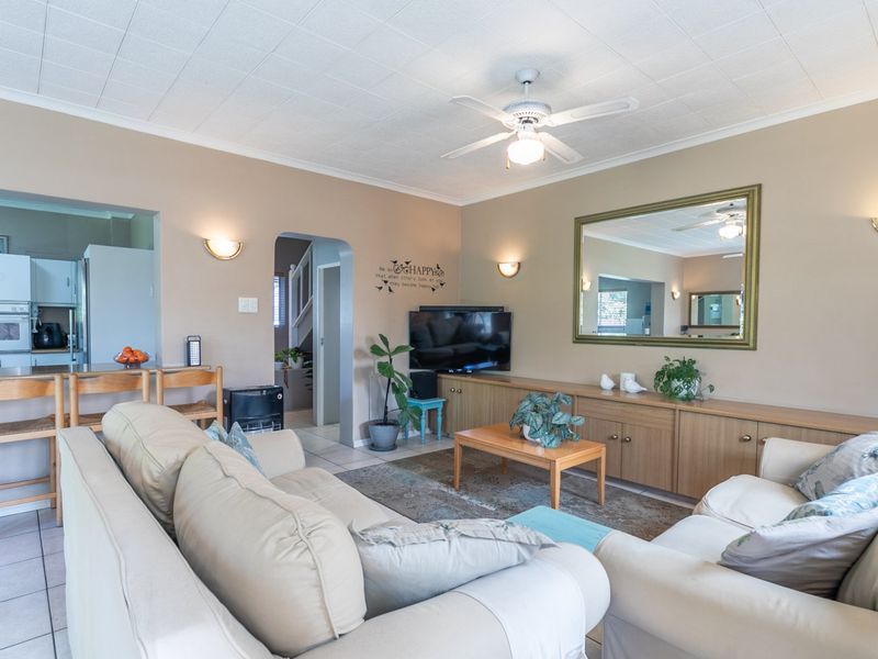 Open plan living area featuring tiled floors, ceiling fan, and integrated kitchen cabinetry with built-in appliances, creating a functional and connected living space.