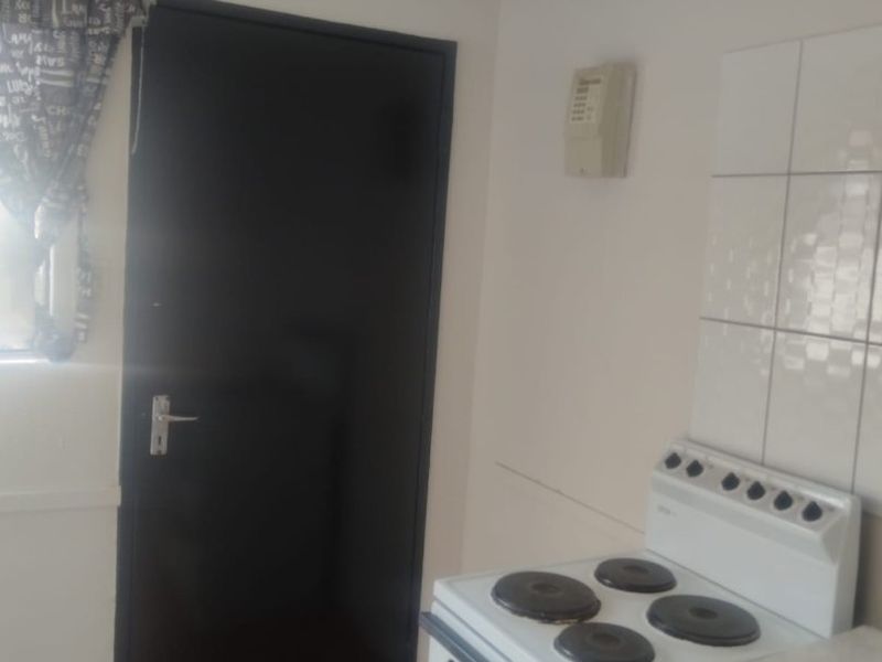 A functional kitchen area featuring a freestanding electric stove, tiled splashback, and tiled flooring.
