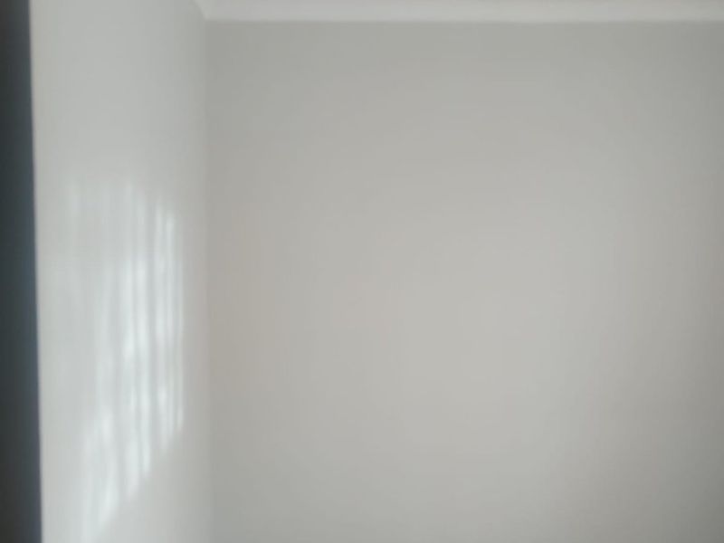 A simple, empty bedroom featuring neutral painted walls and tiled flooring, providing a blank canvas for personalization.