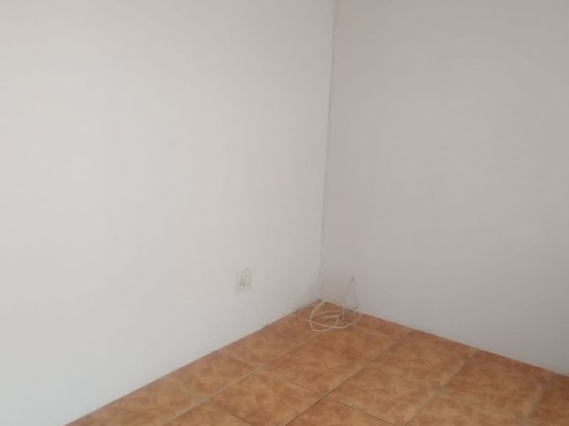An empty bedroom featuring neutral painted walls and ceramic floor tiles, providing a blank canvas for interior design.