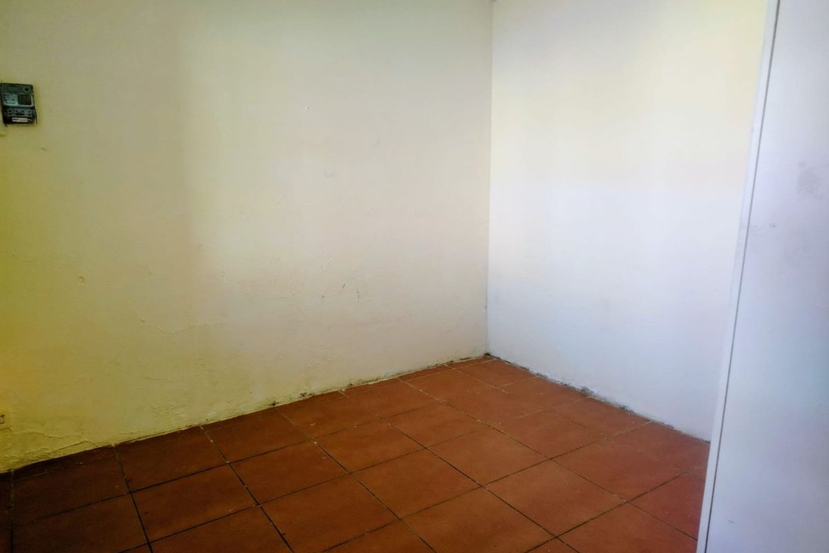An empty bedroom featuring tiled flooring and coving, requiring cosmetic updates to the wall finishes.
