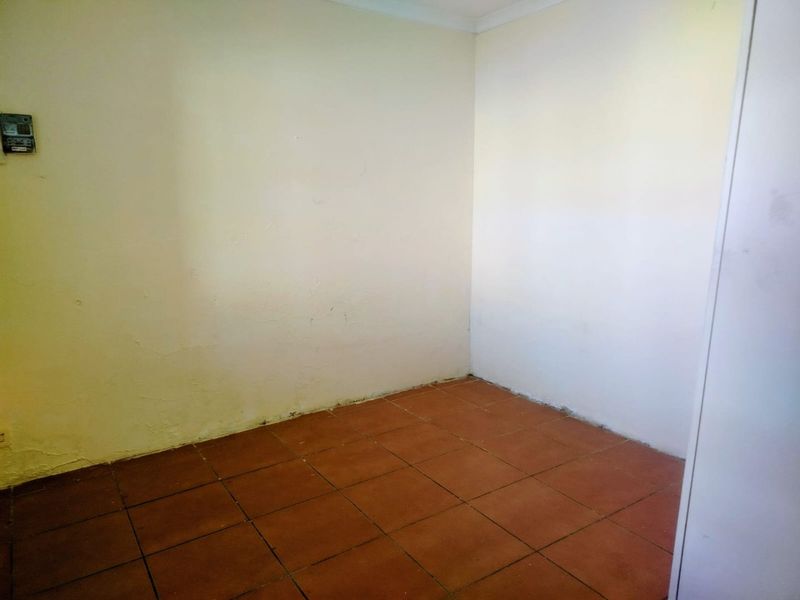An empty bedroom featuring tiled flooring and coving, requiring cosmetic updates to the wall finishes.