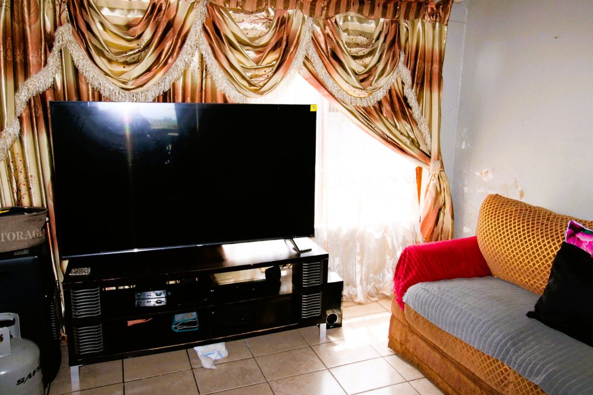 Living room area featuring tiled flooring and visible wall surface damage, requiring cosmetic attention.