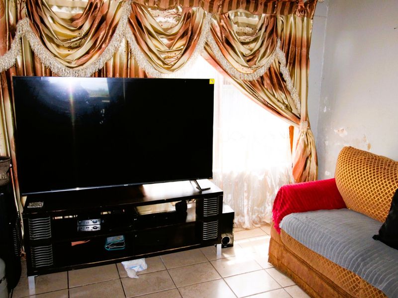 Living room area featuring tiled flooring and visible wall surface damage, requiring cosmetic attention.