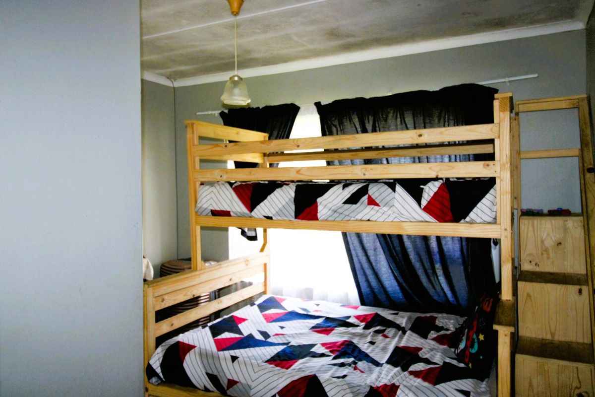 A bedroom featuring a bunk bed setup with visible ceiling staining and signs of wear on the wall finishes.