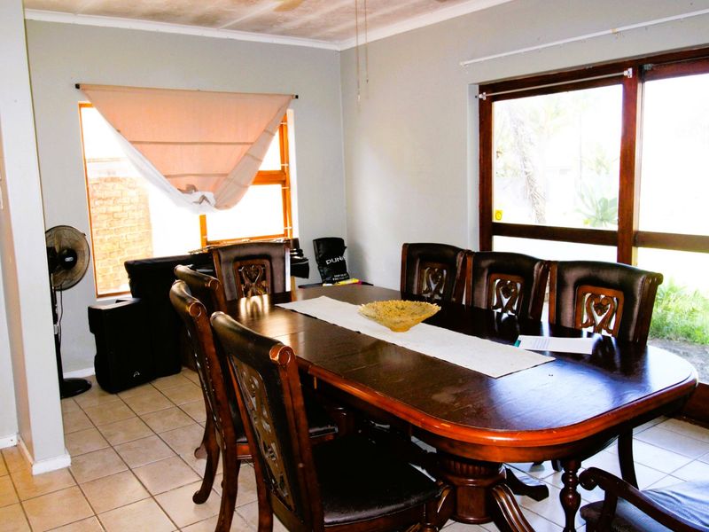 Dining room featuring tiled flooring, large windows, and sliding glass door access to the exterior, showing signs of ceiling water damage.