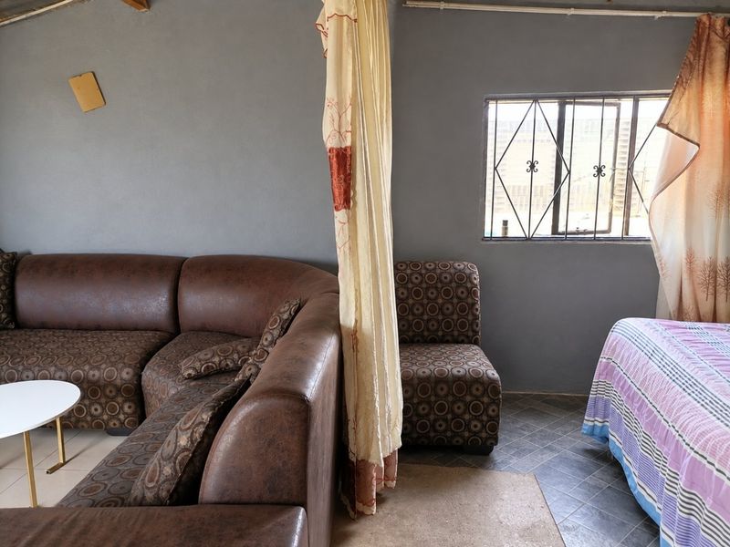 A living area featuring tiled flooring and a window with security bars, requiring cosmetic updates to the walls and ceiling.