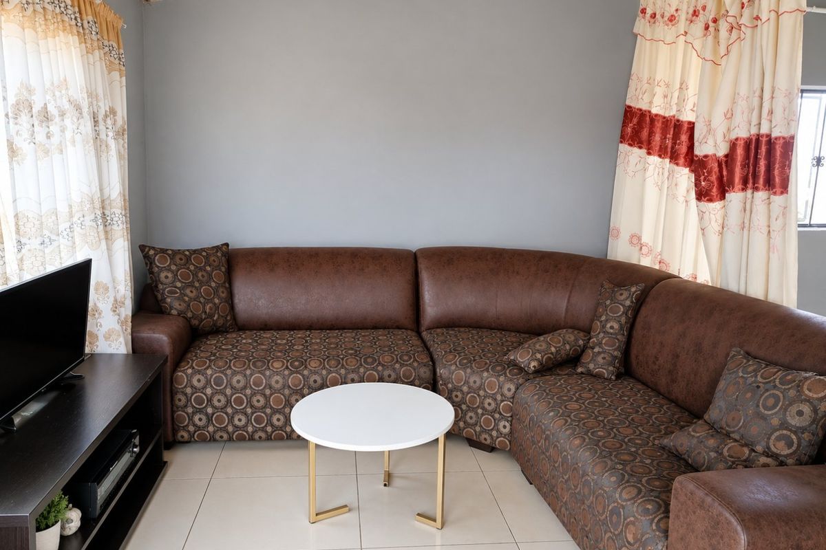 A comfortable living room featuring neutral tiled flooring and grey painted walls, providing a functional and well-lit space for relaxation.