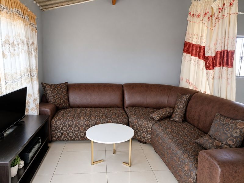 A comfortable living room featuring neutral tiled flooring and grey painted walls, providing a functional and well-lit space for relaxation.