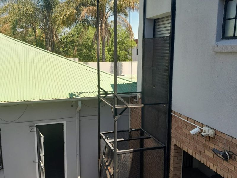 Exterior view of a commercial property featuring an external goods lift, security camera, and access to a rear building entrance.