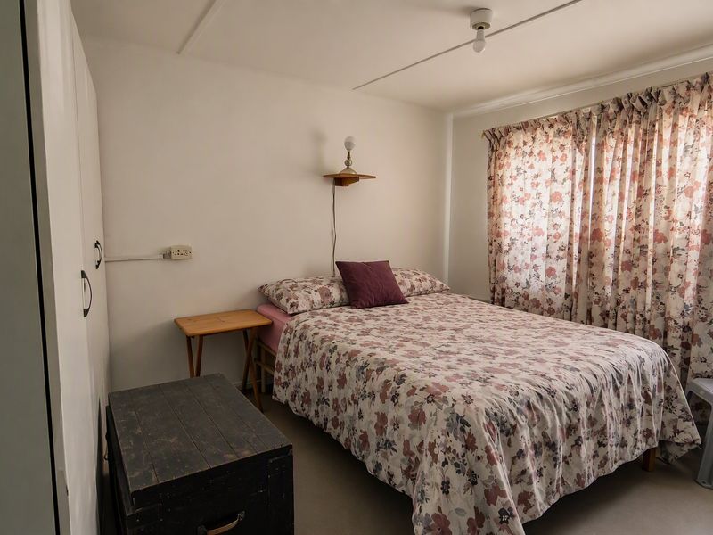 A functional bedroom featuring built-in wardrobe storage and a wall-mounted light fixture, offering a neutral base for potential interior updates.
