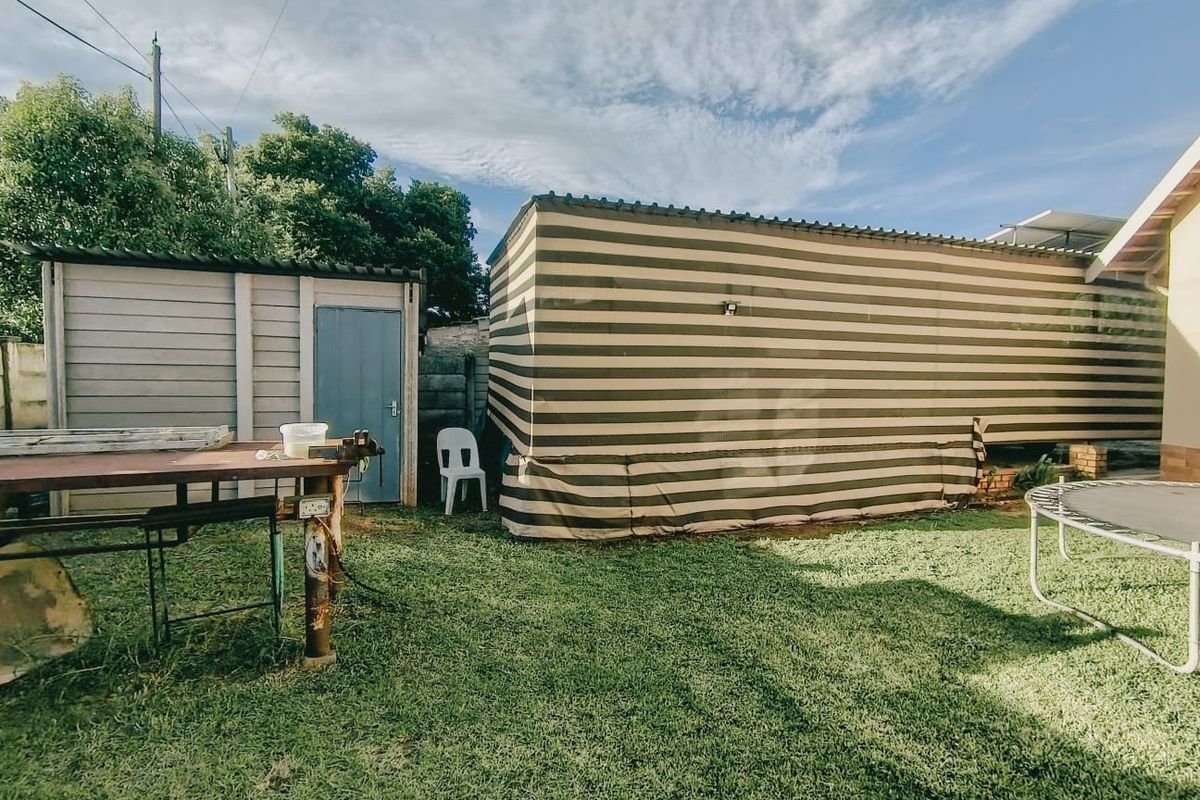 Rear garden area featuring a prefabricated storage shed and lawn space, providing functional outdoor utility storage.