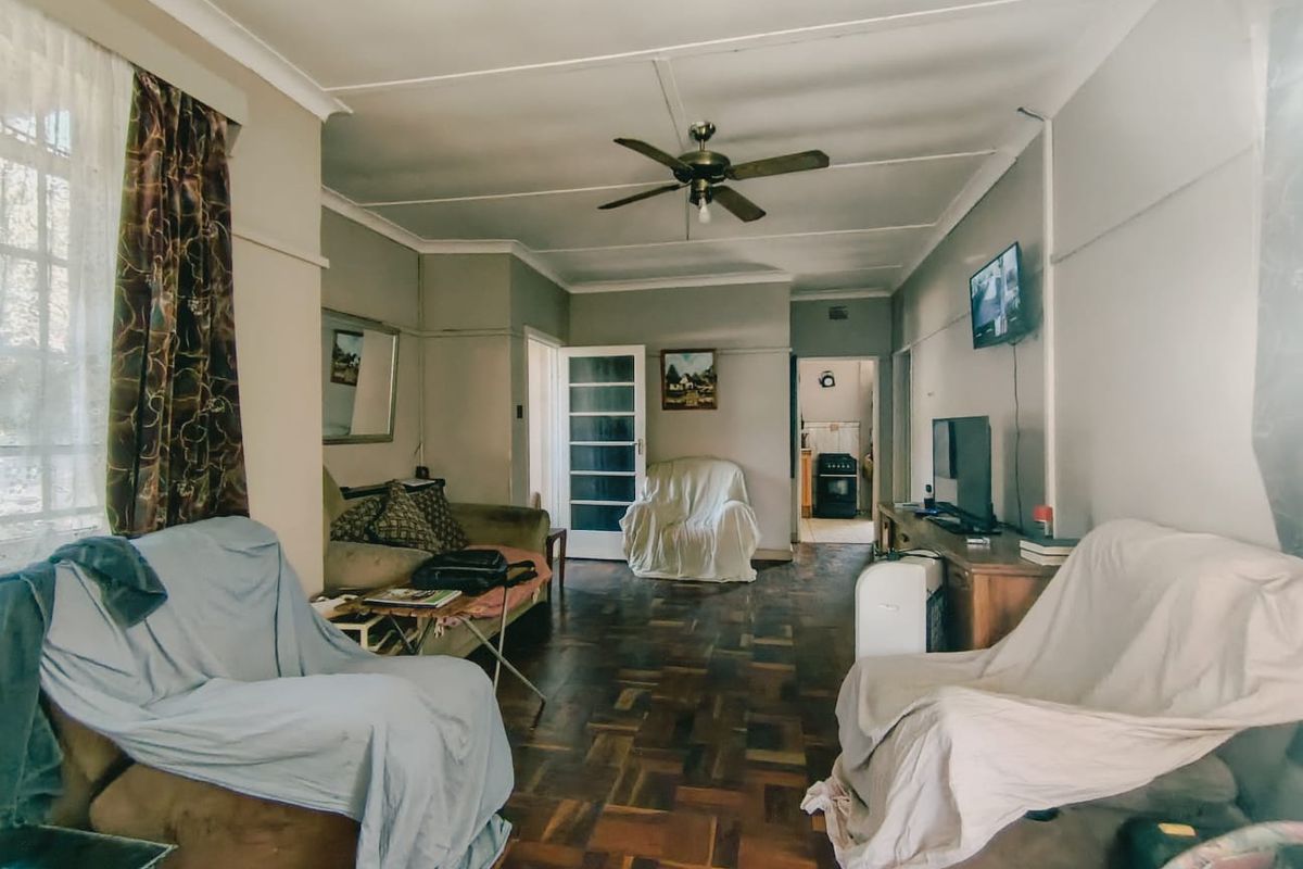 A living room featuring traditional parquet flooring, a ceiling fan, and coved cornicing, offering a classic layout with access to adjacent rooms.
