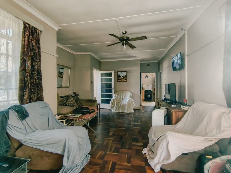 A living room featuring traditional parquet flooring, a ceiling fan, and coved cornicing, offering a classic layout with access to adjacent rooms.