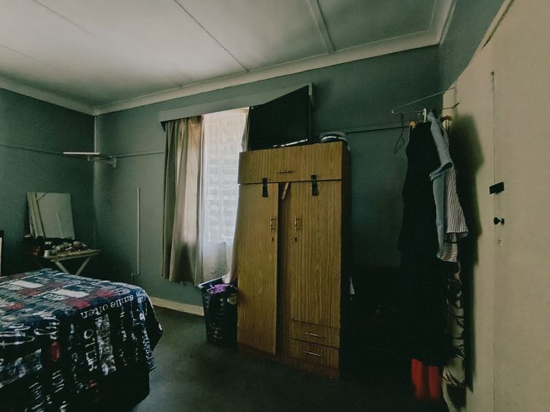 A bedroom featuring a built-in wardrobe and standard ceiling cornicing, currently requiring cosmetic updates to improve the overall aesthetic and condition.
