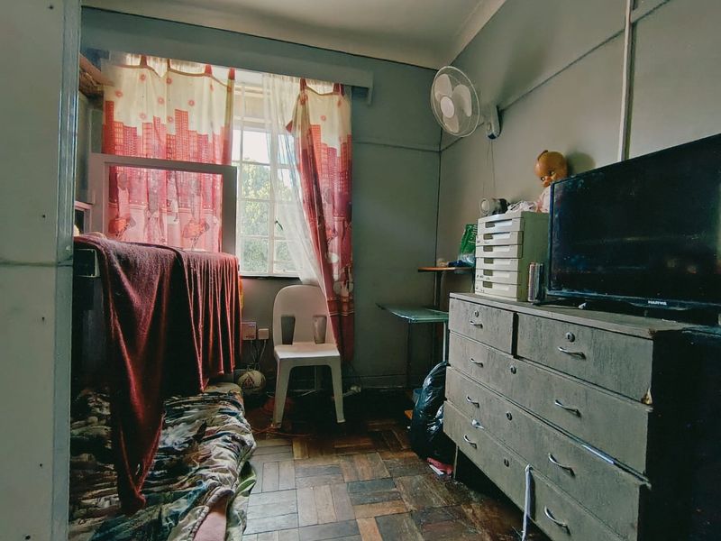 A bedroom featuring parquet flooring and a wall-mounted fan, requiring cosmetic updates to improve its overall condition and appeal.