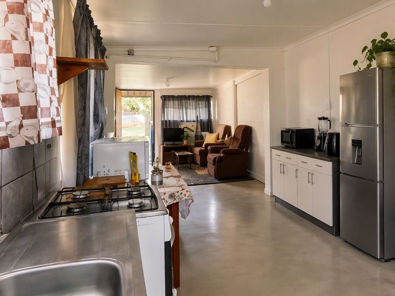 Open plan kitchen and living area featuring concrete flooring, built-in cabinetry, and a gas stove, providing a functional and connected living space.