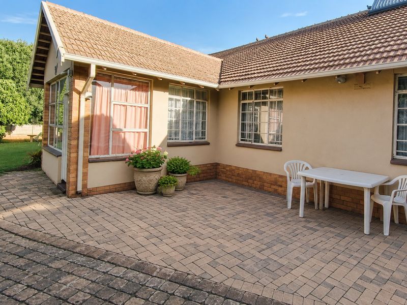 A paved outdoor patio area featuring brick accents and views of the surrounding garden, providing a functional space for outdoor relaxation.