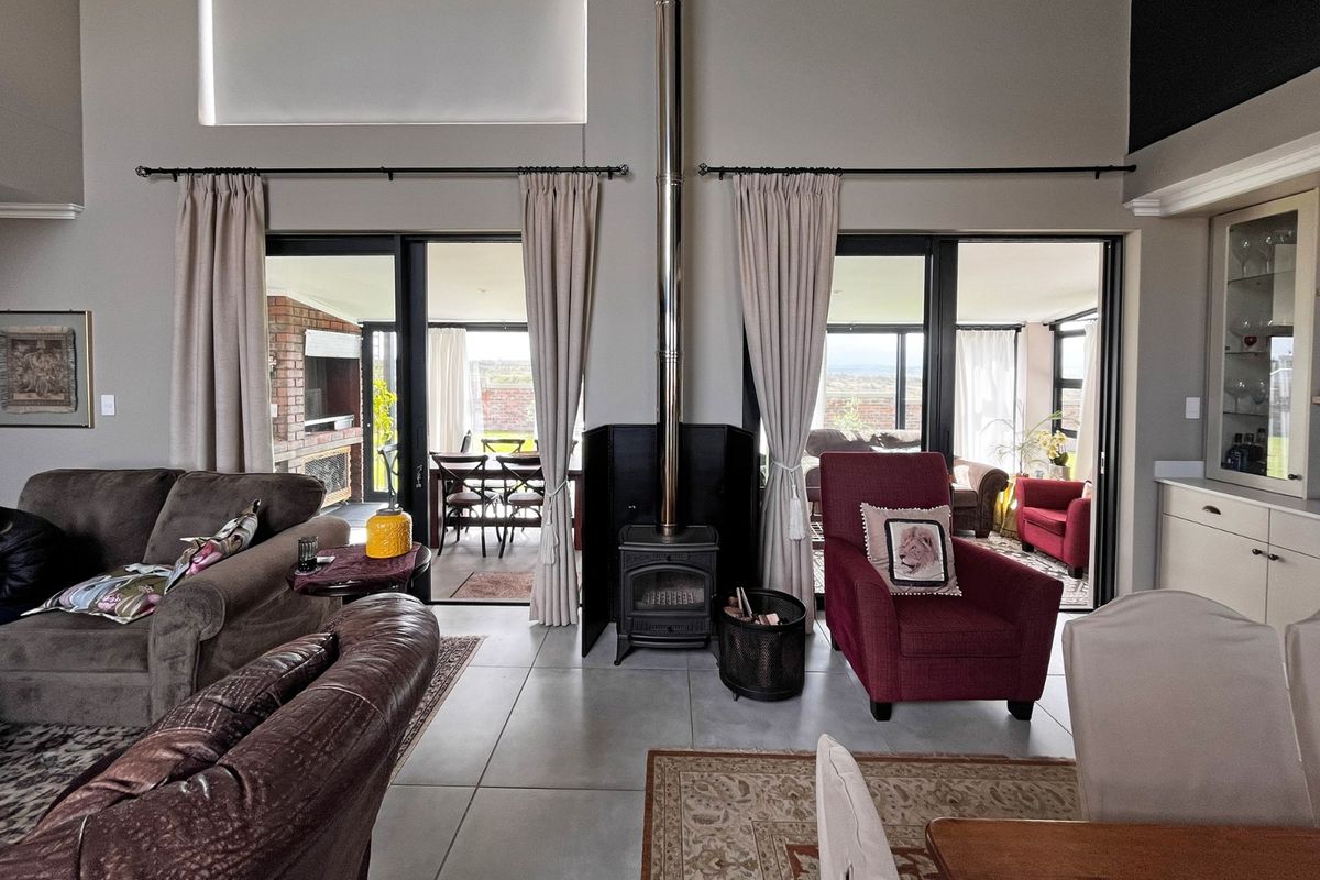 Spacious living room featuring a central freestanding fireplace, high ceilings, and large sliding glass doors that provide seamless access to the outdoor patio area.