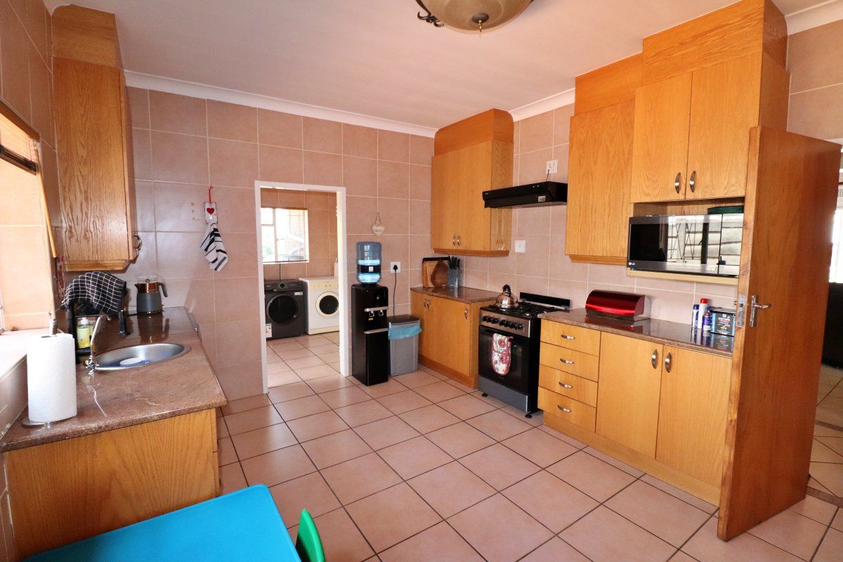 A functional kitchen featuring wooden cabinetry, granite countertops, tiled walls and flooring, and a built-in oven with an extractor fan.