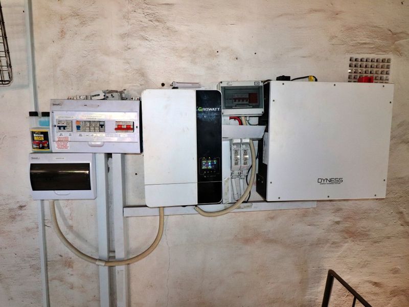 Utility area featuring a wall-mounted solar inverter and Dyness energy storage system with associated electrical distribution board.